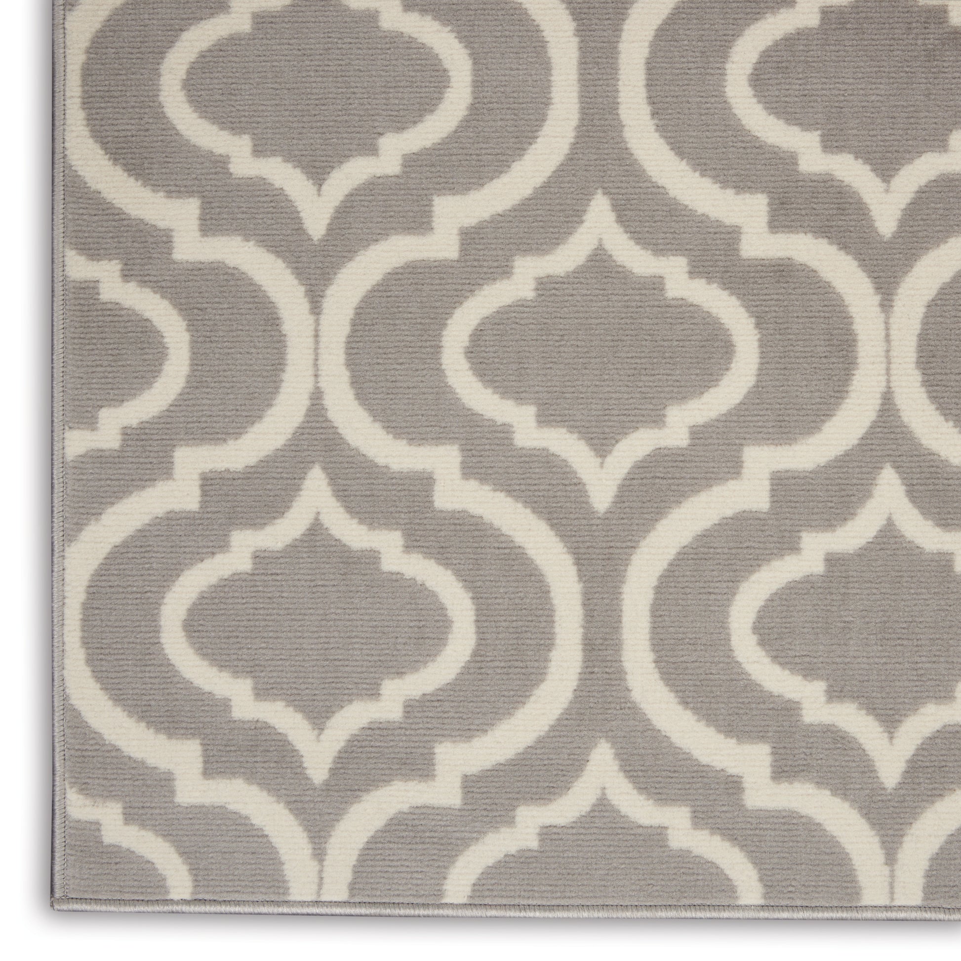 Gray rug with white trellis pattern, woven texture and geometric lattice; edge visible.