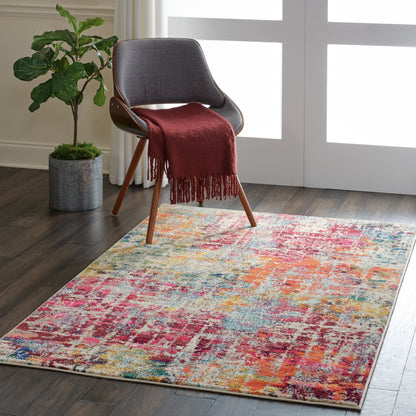 Gray mid-century lounge chair with wooden legs, burgundy fringe throw, and a bright multicolor abstract rug by a potted plant.
