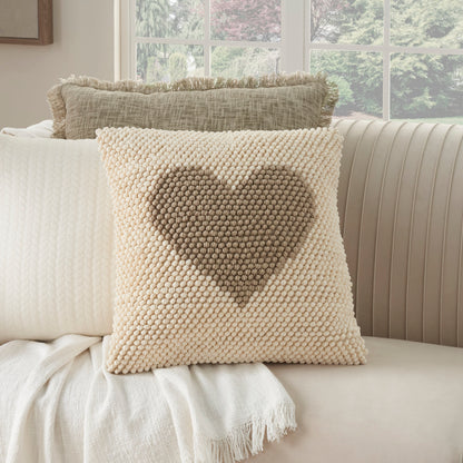 Cream boucle knit throw pillow with a dark beige heart design on a light sofa.