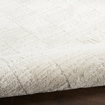 Cream plush rug with a subtle geometric pattern on a dark wood floor.