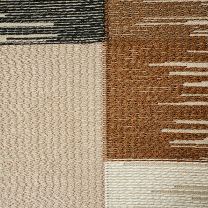 Close-up of a patchwork area rug with beige, tan and brown blocks and textured striped accents.