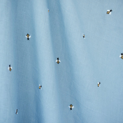 Light blue fabric with tiny honey bee embroidery scattered across.