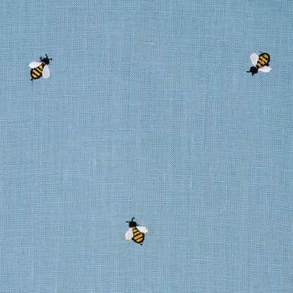 Light blue woven fabric with small embroidered yellow-and-black bees.