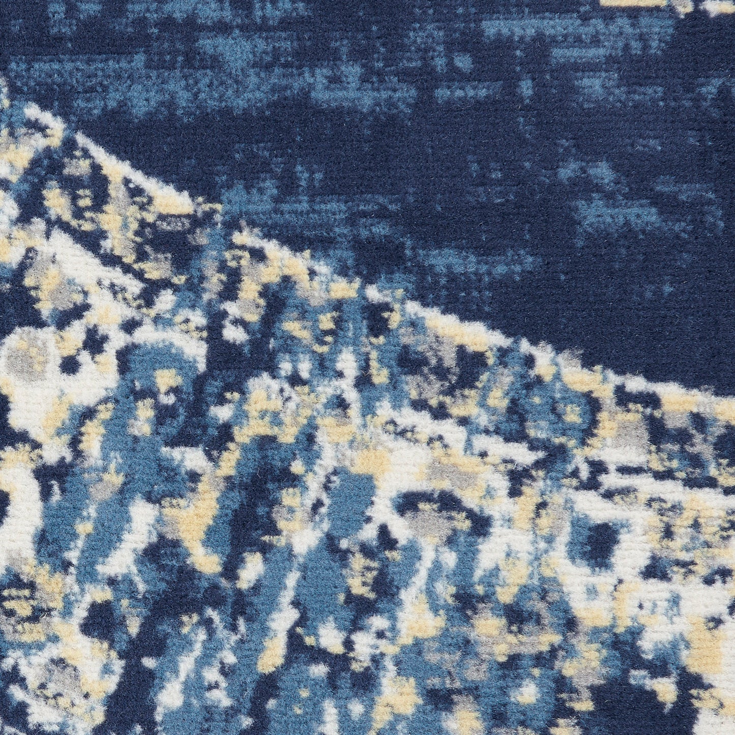 Close-up of a blue abstract rug with navy, teal, cream & pale yellow tones; plush textured pile, modern distressed pattern.