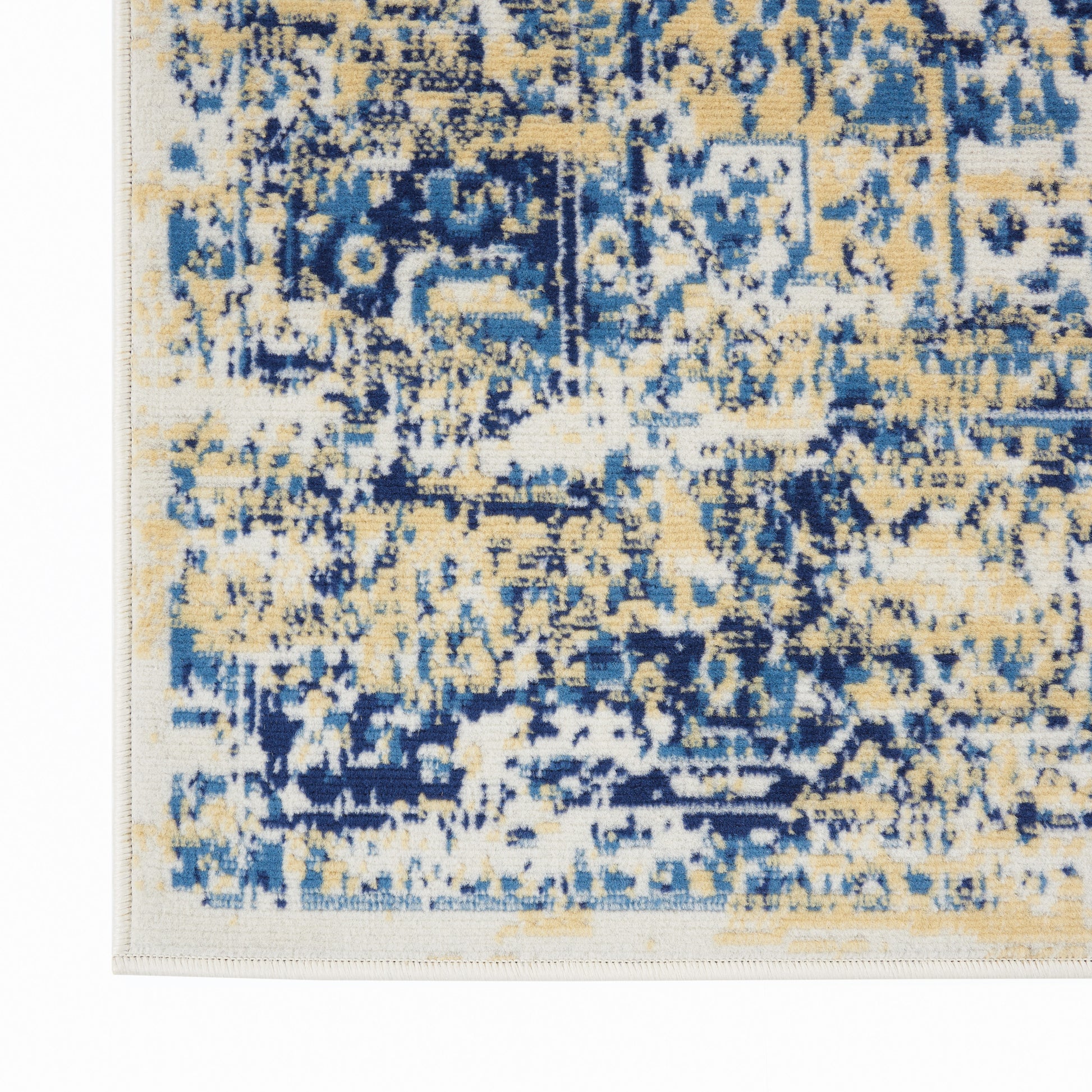 Close-up of an abstract distressed blue and beige area rug corner with a pale border.