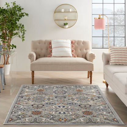 Beige tufted loveseat with rolled arms and wooden legs in a bright living room with a blue-gray rug and orange accents.