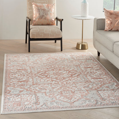 Peach and ivory oriental-pattern area rug on light wood floor, paired with beige chair, gray sofa, and blush cushions.