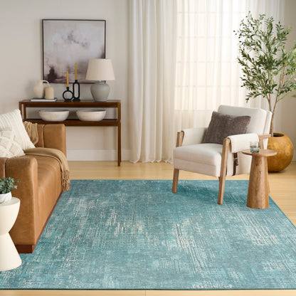 Teal distressed area rug anchors a living room with tan leather sofa, cream armchair, wood furniture, and a potted plant.