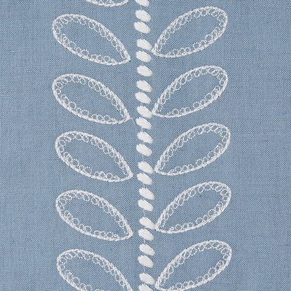 Blue fabric featuring white embroidered leaf motifs arranged along a central vertical line; delicate lace-like stitching.