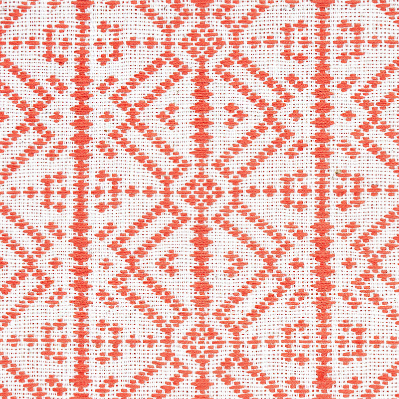 Orange-red geometric lattice embroidery on white fabric; diamond motifs with cross accents in a traditional textile pattern.
