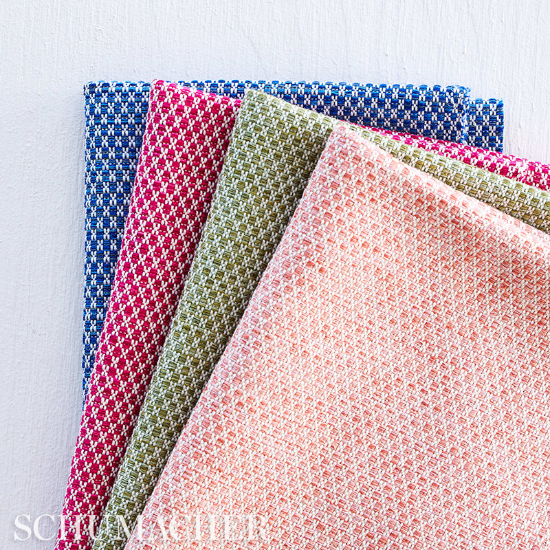 Set of woven napkins in blue, red, olive, peach and pink with tiny checker pattern, folded in a colorful fan.