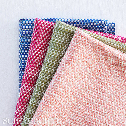 Set of woven napkins in blue, red, olive, peach and pink with tiny checker pattern, folded in a colorful fan.