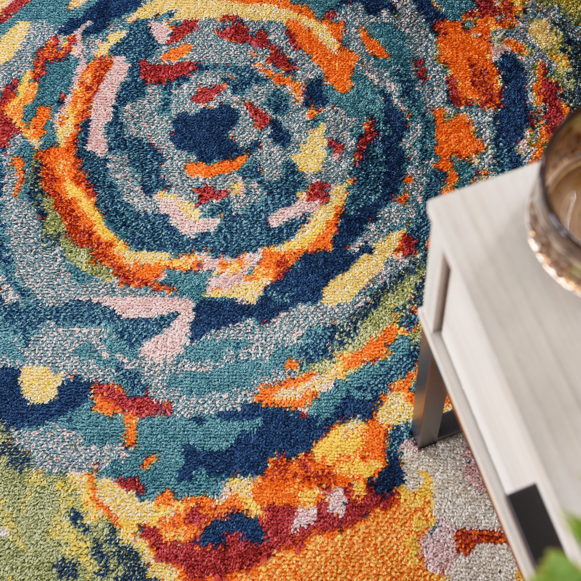 Colorful rectangular rug with blue, teal, orange & yellow swirl pattern; light wood coffee table nearby.