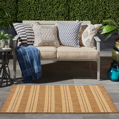 Beige outdoor rug with orange stripes; cushions in striped, geometric, and paisley patterns and a blue throw nearby.