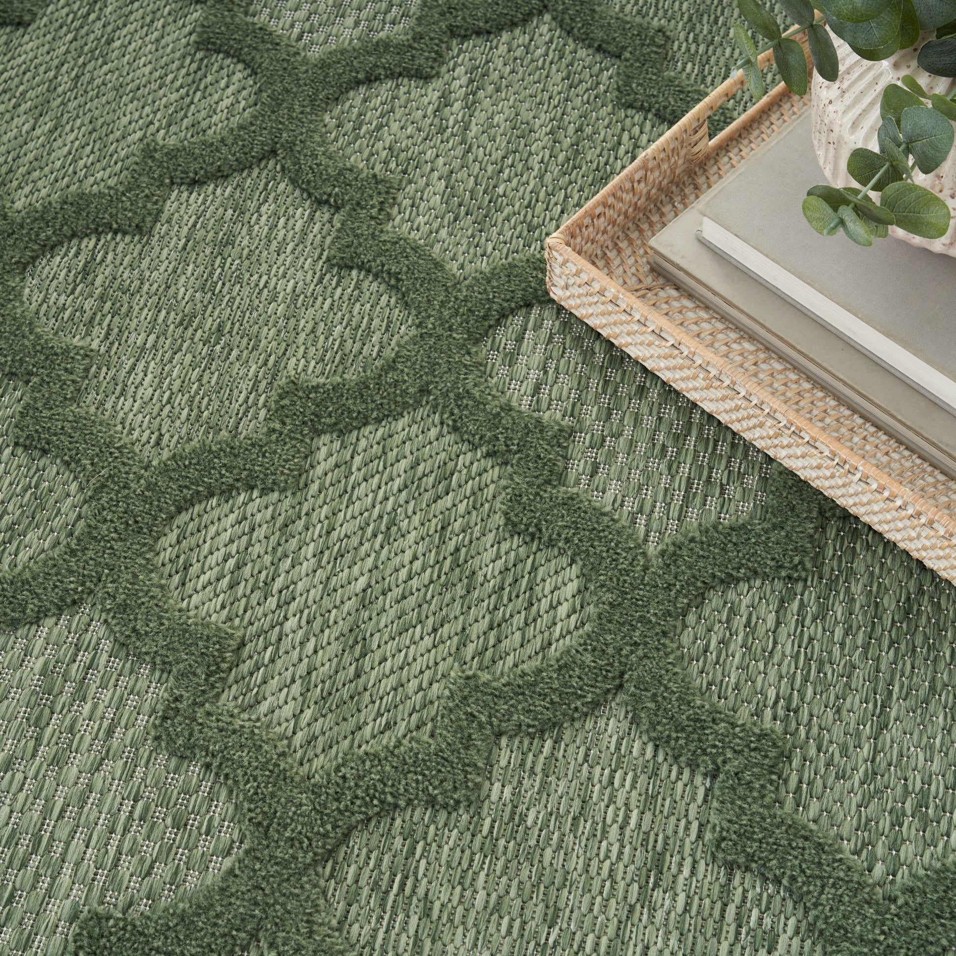 Green woven rug with an interlocking geometric pattern; textured natural-fiber look.