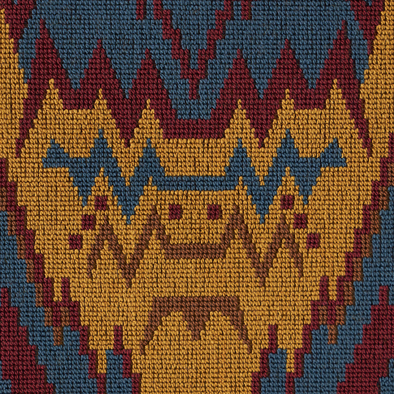 Close-up of a woven textile with bold zigzag and diamond pattern in mustard yellow, teal, and burgundy.