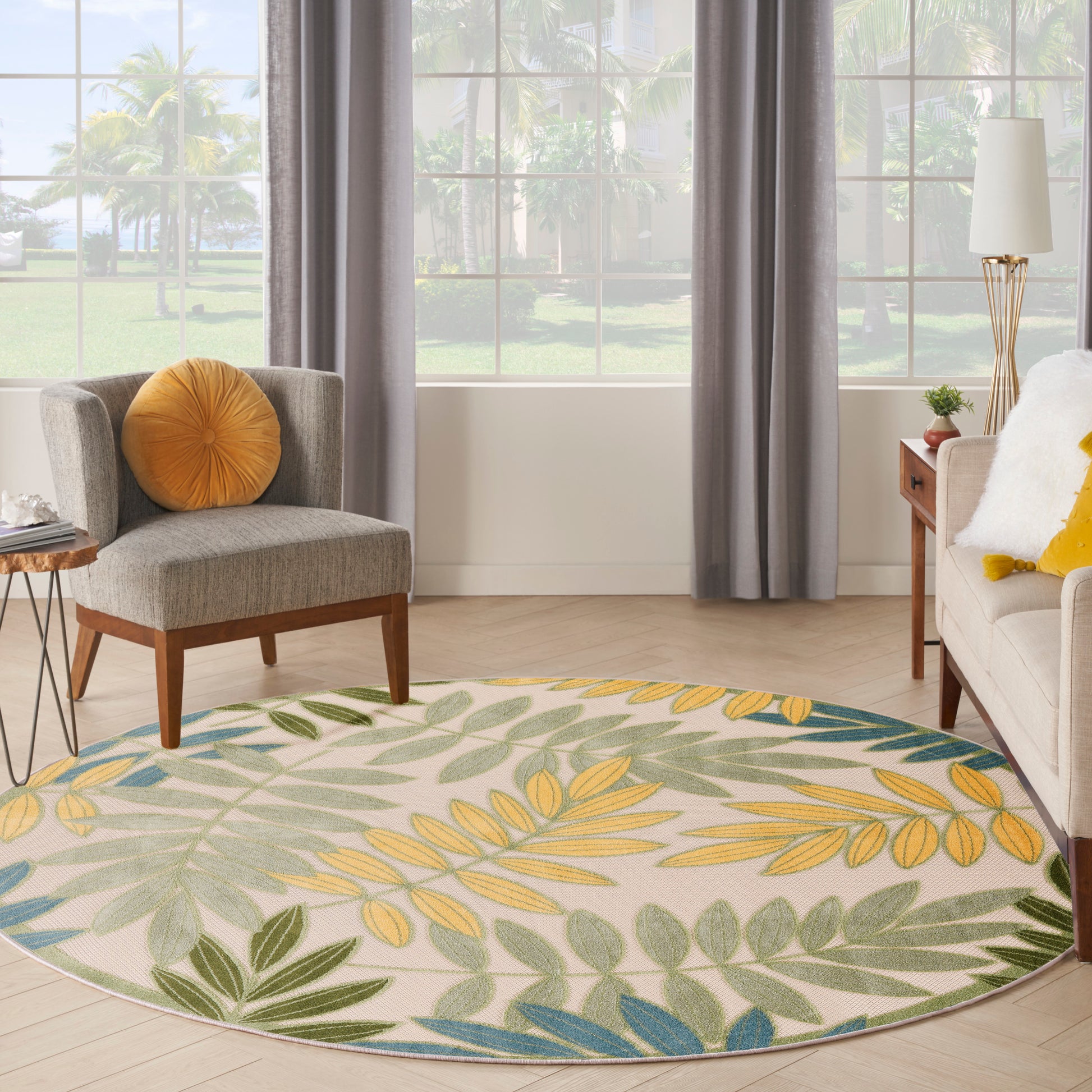Round botanical outdoor rug with yellow, green and blue leaves on cream.