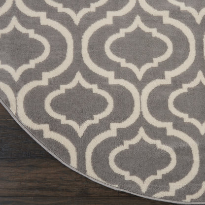 Round grey rug with white trellis pattern on dark wood floor; soft textured, modern floor covering.