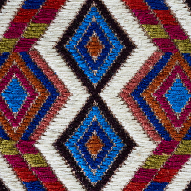 Kilim-style woven rug with diamond geometric motifs in blue, orange, pink, white and black.