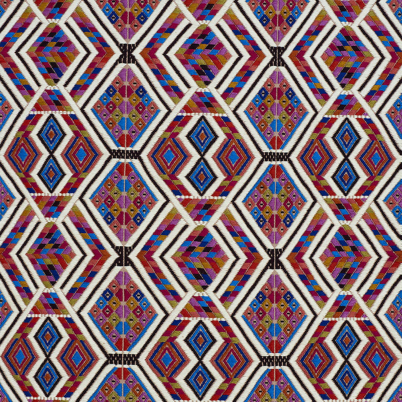 Vibrant geometric diamond lattice textile pattern in red, purple, blue, yellow with white stripes.