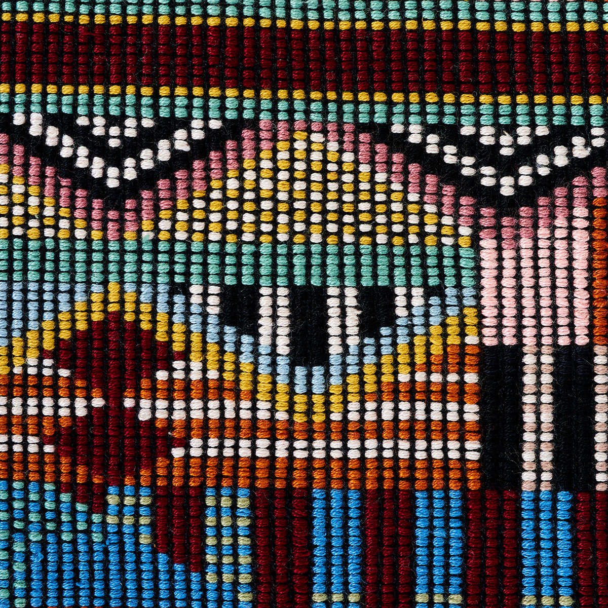 Close-up of multicolor hand-woven brocade textile with a zigzag geometric pattern in turquoise, red, yellow, white, and black.
