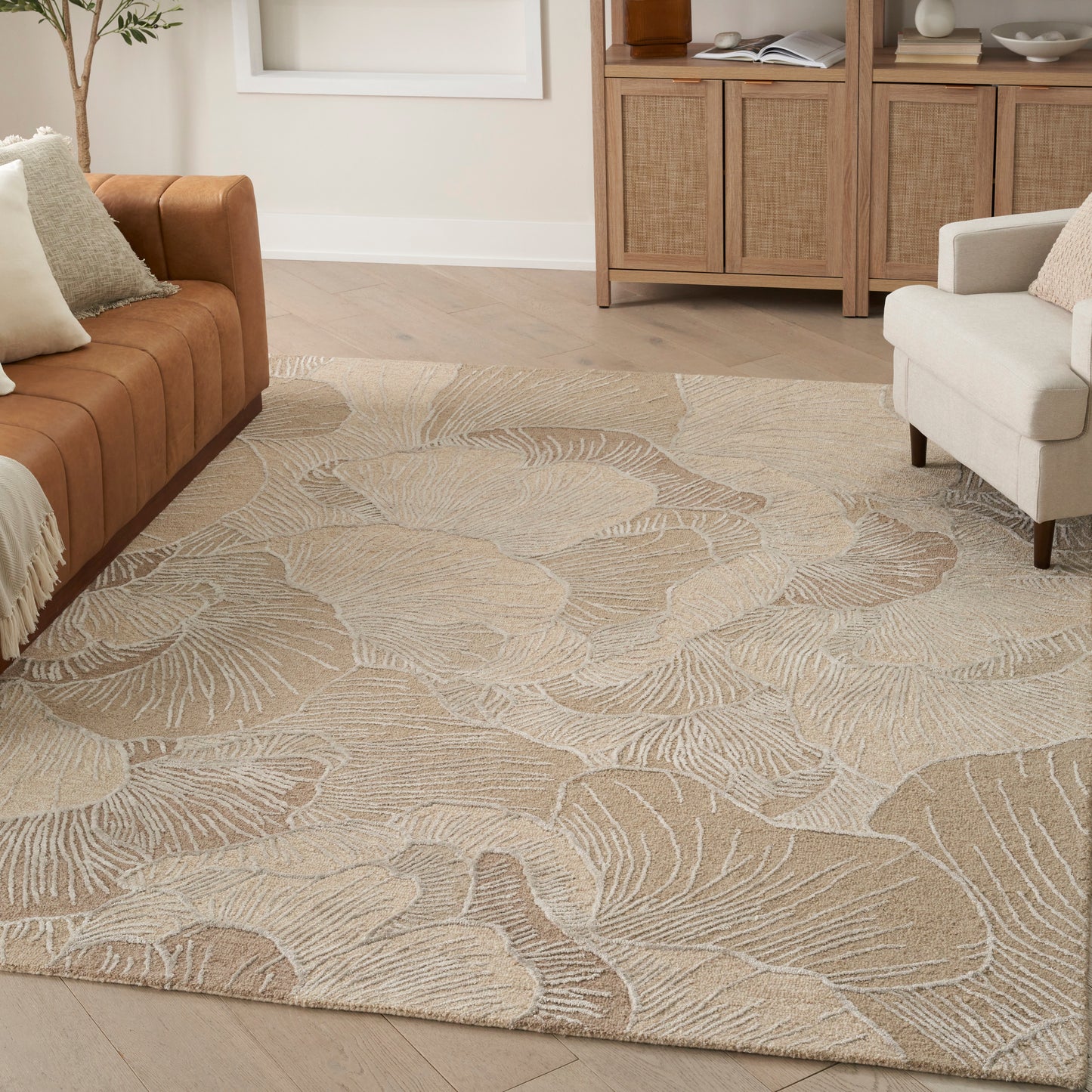Beige textured area rug with a subtle leaf pattern in a light living room with tan sofa and cream chair