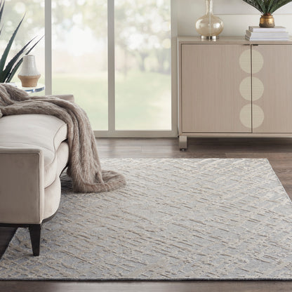 Neutral-toned living room with a textured gray geometric rug, beige sofa, taupe throw, and light wood sideboard.