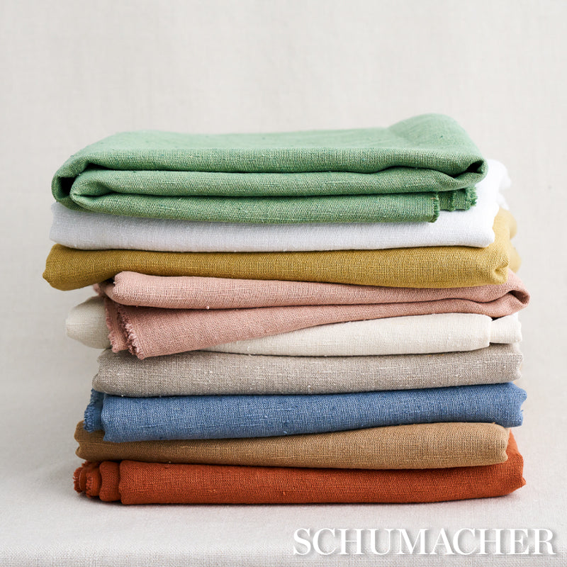 Stack of folded knit fabrics in green, cream, mustard, pink, beige, blue, brown and orange; cozy textile yardage.