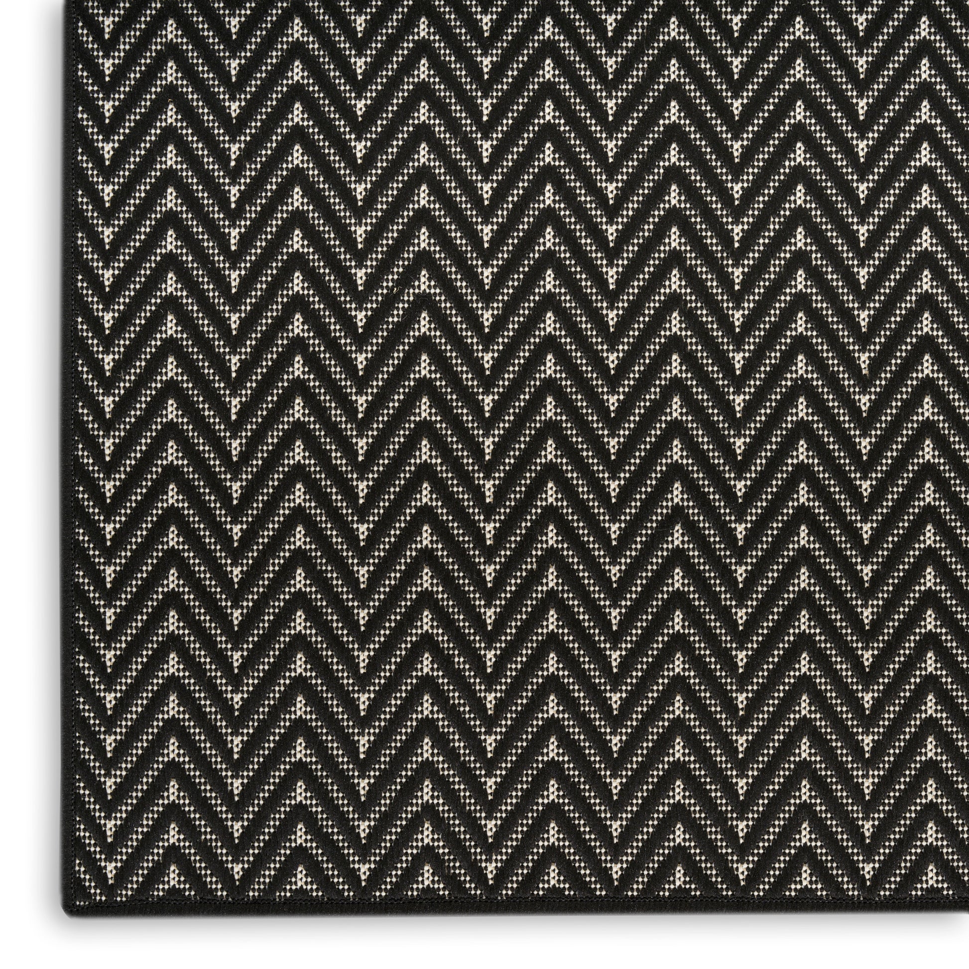 Close-up of black and gray herringbone woven rug with textured chevron pattern.