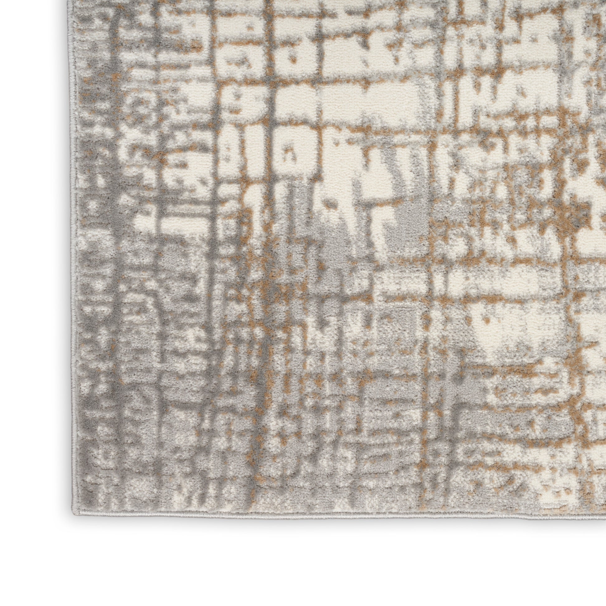 Corner of a textured area rug with a beige base and gray-brown grid-like pattern.