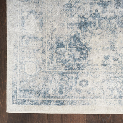 Blue and ivory distressed oriental runner with faded medallion pattern on dark wood floor.