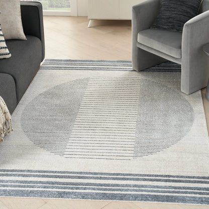 Light gray rectangular area rug with a large circular striped motif in blue-gray tones; modern living room.