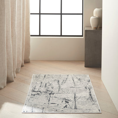 Rectangular gray abstract-pattern rug on light wood floor in a bright minimalist room with beige curtains.