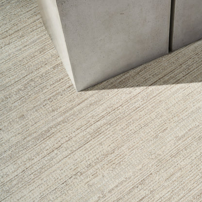 Gray modern rug with a concrete-like texture on a beige striped carpet; minimalist contemporary decor element.