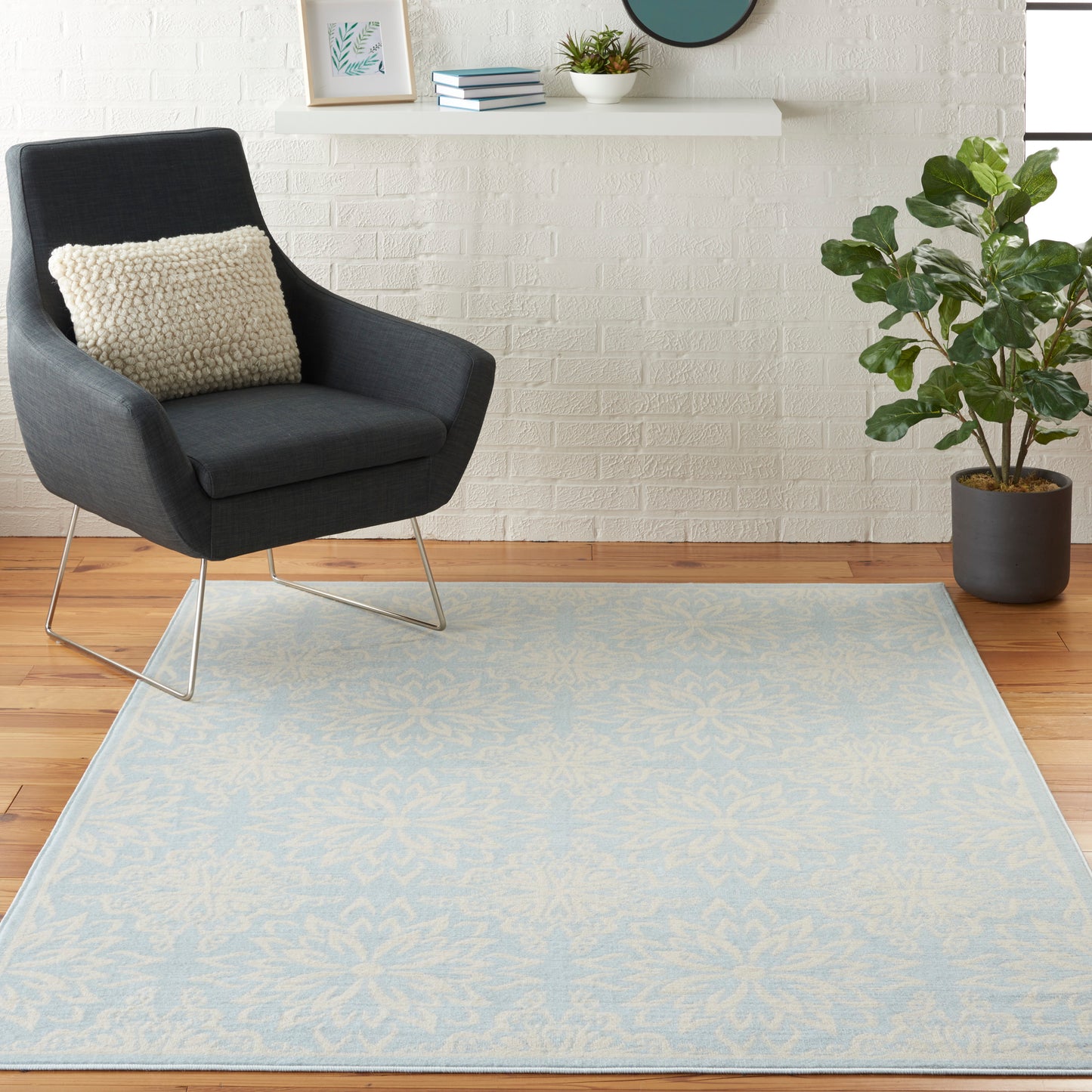 Light blue patterned area rug, 5' x 7', in a bright room with white brick wall.