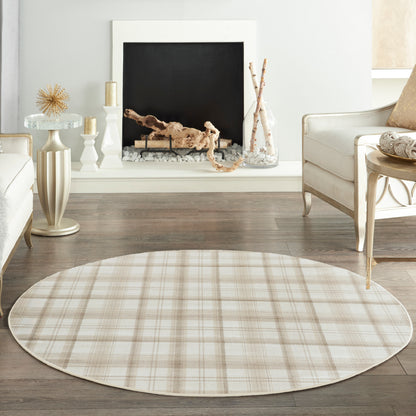 Round beige plaid area rug on dark wood floor in a neutral living room with cream furniture and a fireplace.