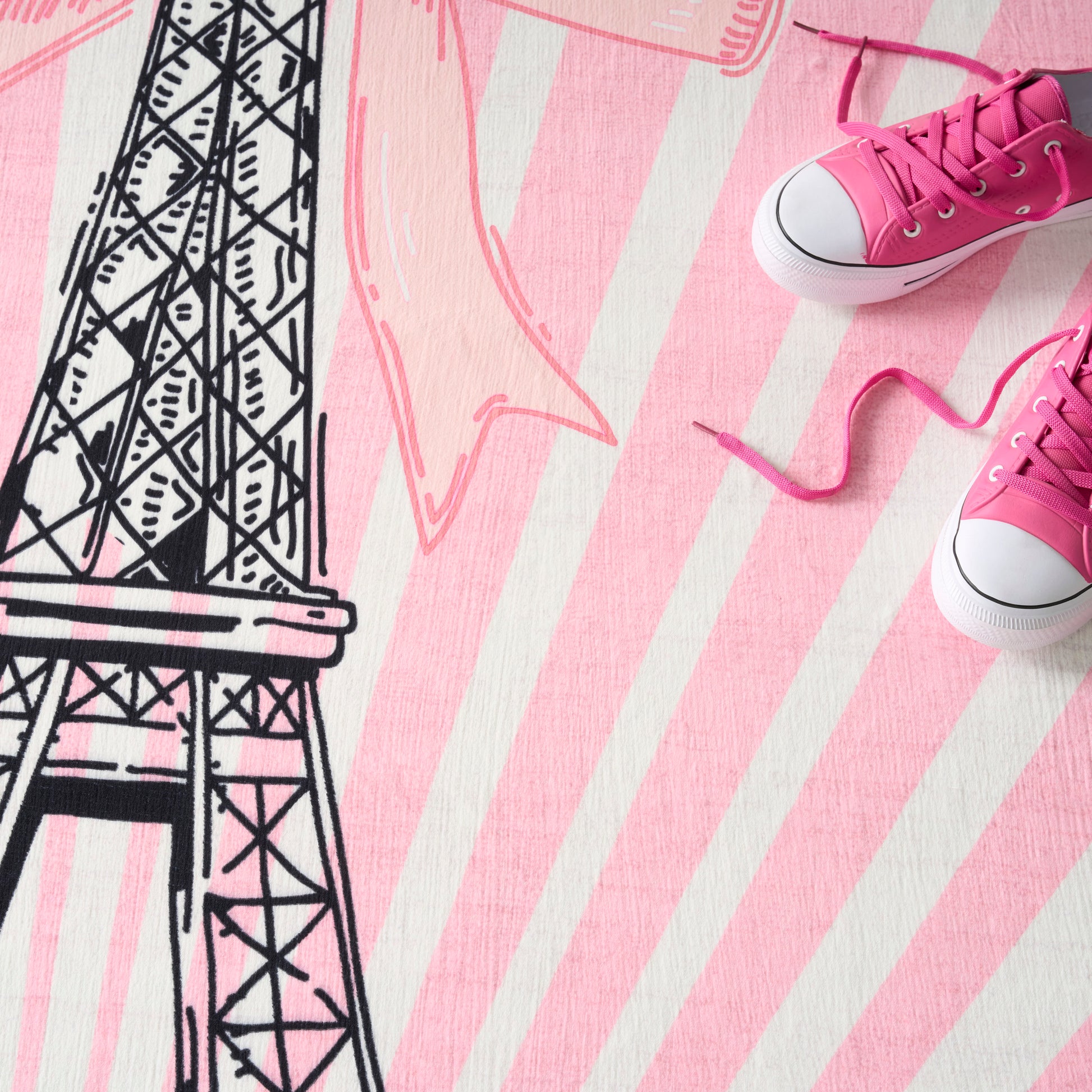 Pink rug with white stripes and a black Eiffel Tower sketch.