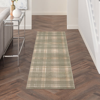 Green plaid hallway runner rug on a dark wood herringbone floor, with a glass console table and white walls.