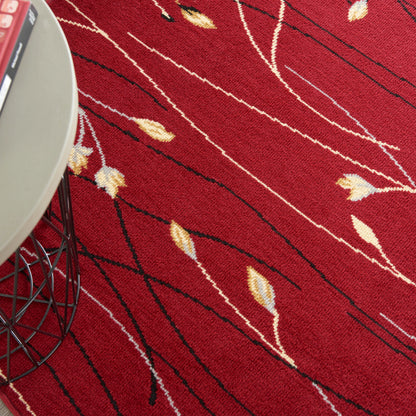 Red rug with black and white wavy lines and beige leaf shapes; metal wire table leg visible at edge.