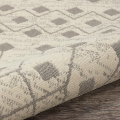 Beige woven round rug with taupe diamond lattice pattern, rolled up on a wooden surface.