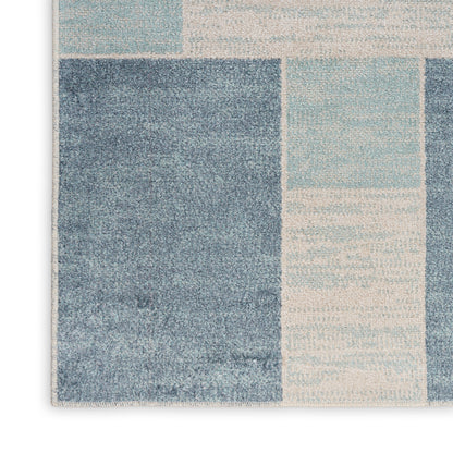Rectangular patchwork rug in navy, denim, and sky blue blocks; textured woven surface.