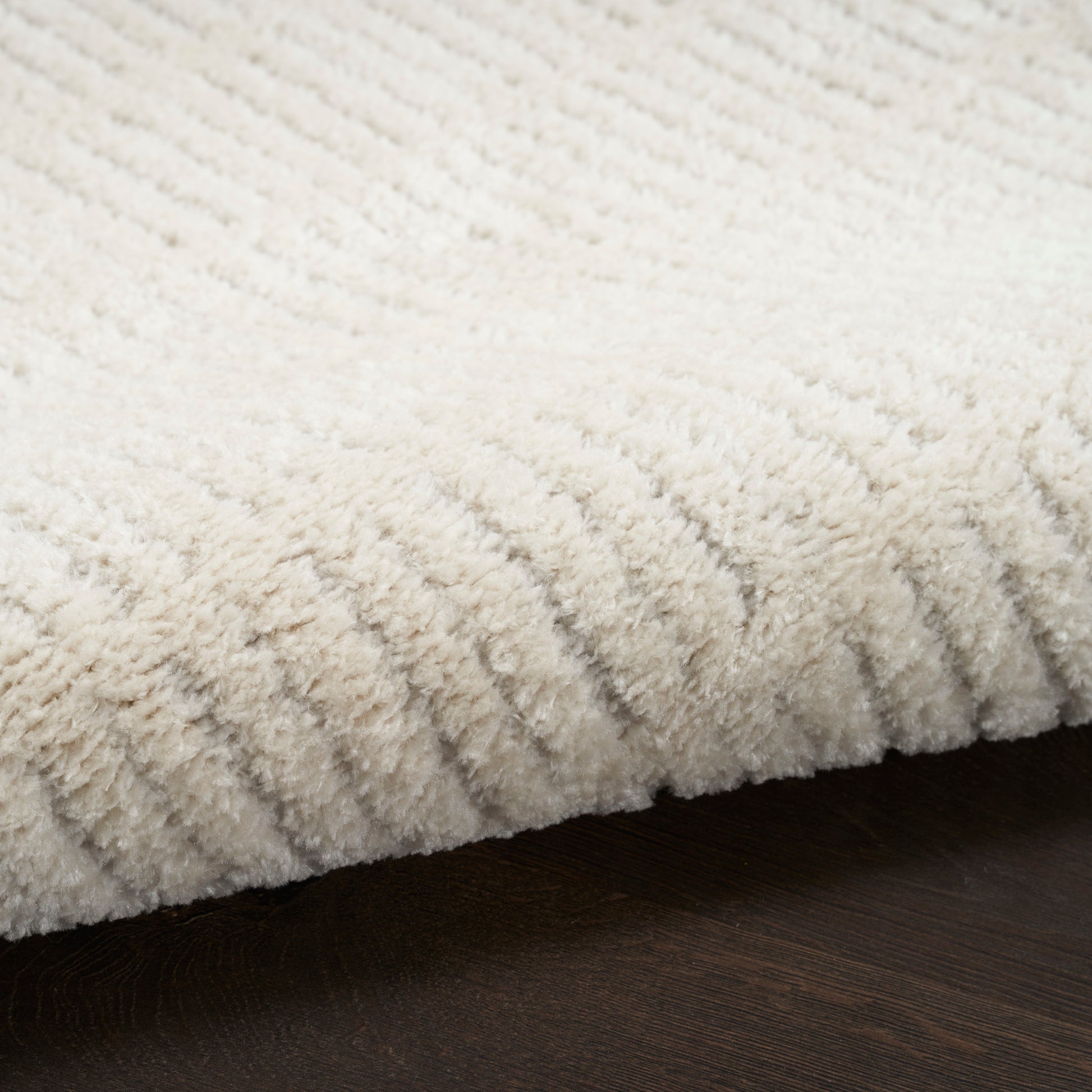 Cream shag rug with dense, fluffy pile on a dark wooden floor.