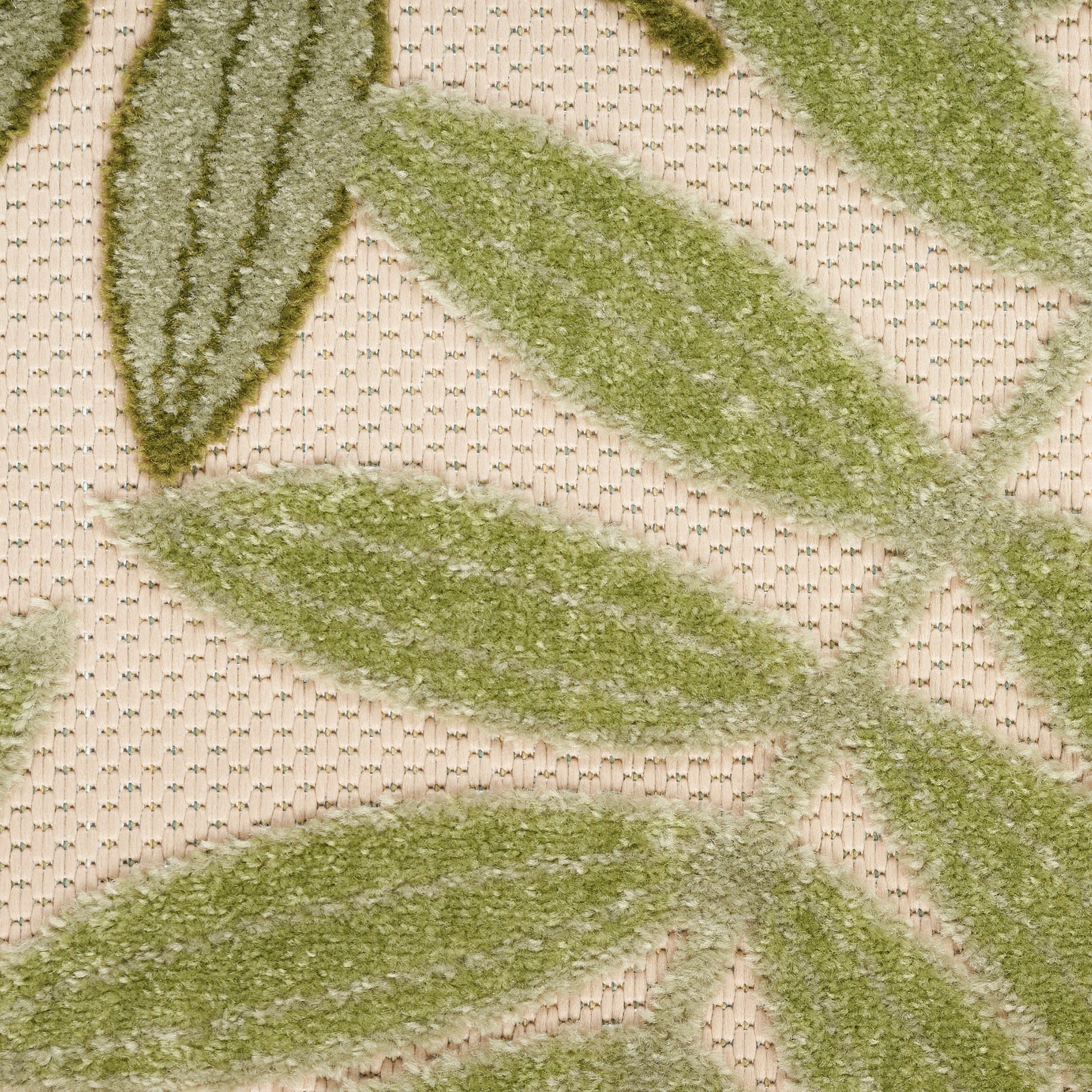 Close-up of moss-green leaf-patterned rug with plush pile on beige woven background
