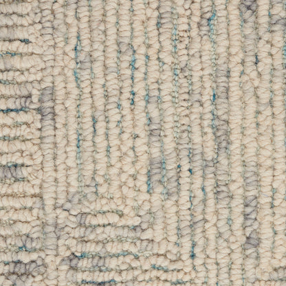 Beige tufted rug close-up with chunky loop pile and pale blue vertical accents; soft, woven wool look.