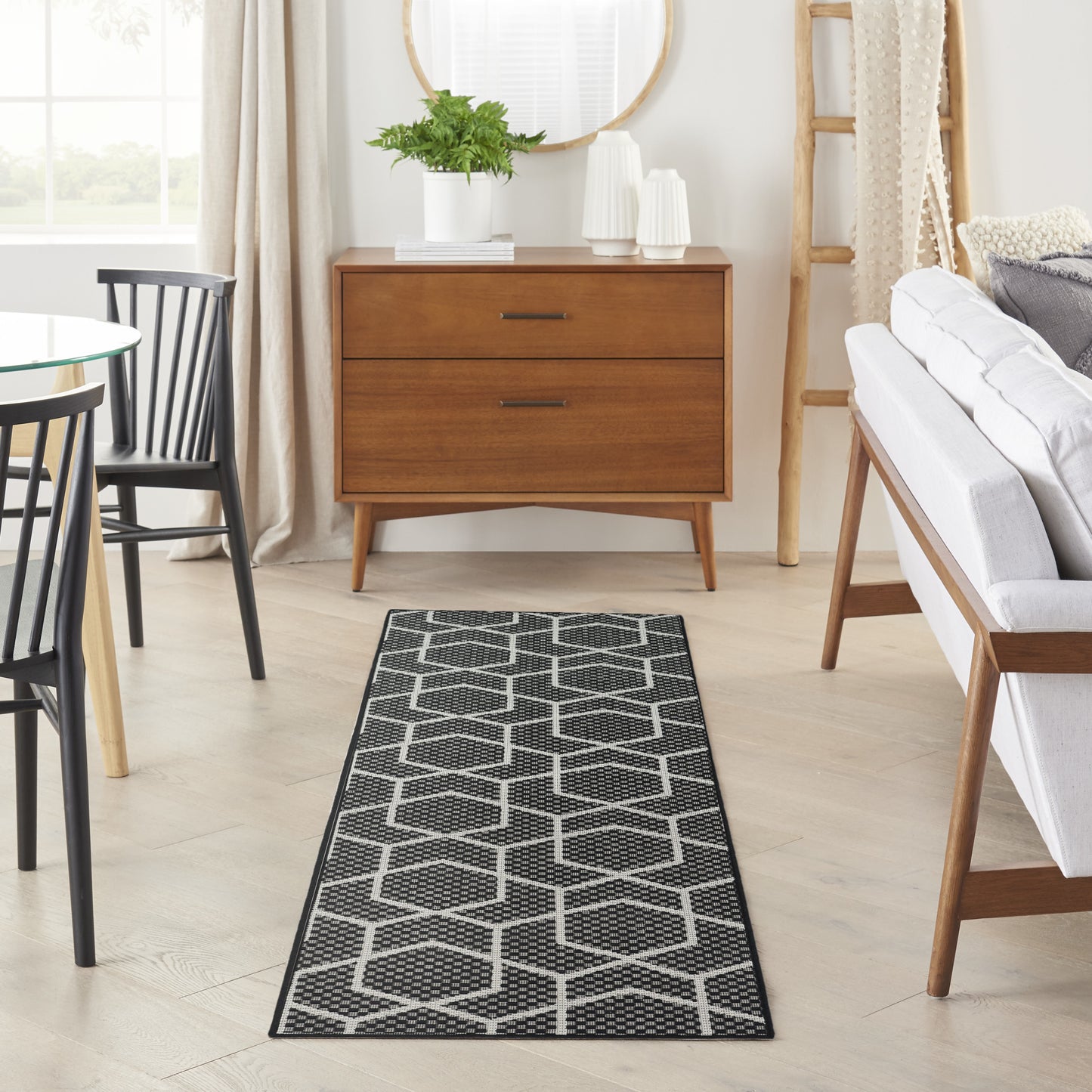 Geometric black-gray 8' runner rug in a neutral living room, with a plant and a round mirror.
