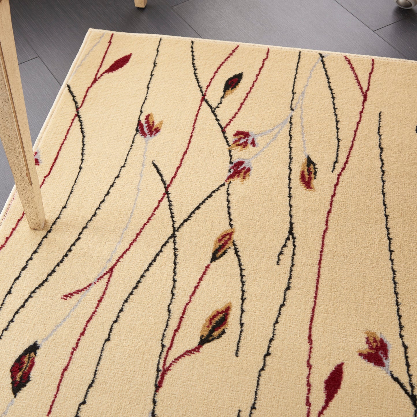 Beige area rug with abstract red, black & pale blue vine-like lines and leaf motifs.