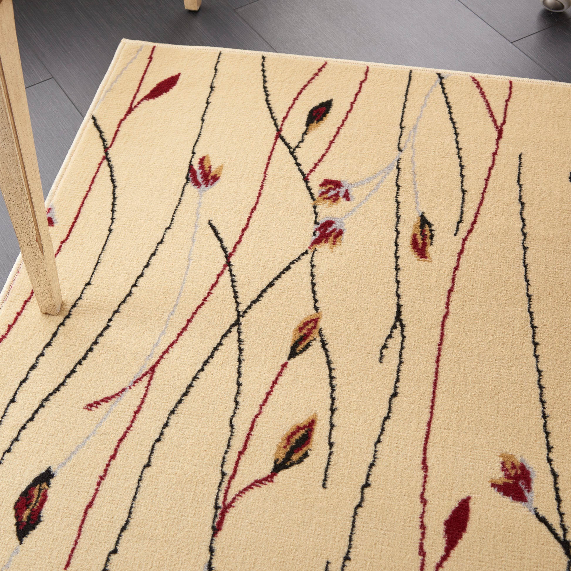 Beige area rug with abstract red, black & pale blue vine-like lines and leaf motifs.