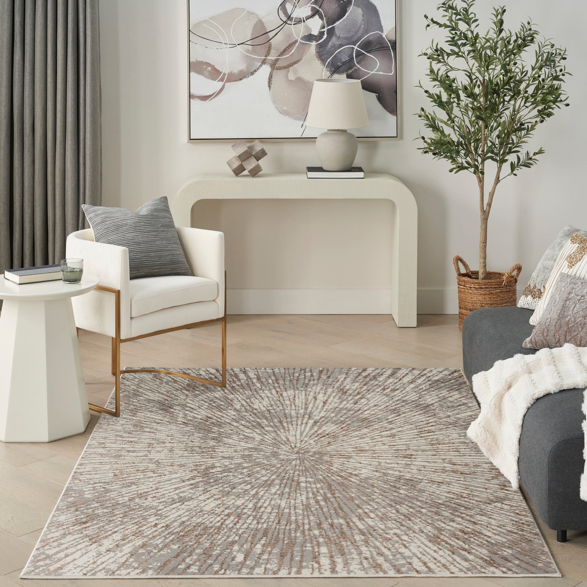 Neutral living room with curved beige console, white armchair, grey sofa, starburst rug, abstract art, and tall potted plant.