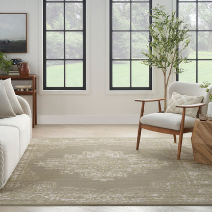 Neutral living room with beige patterned rug, mid-century wooden chair, white sofa, potted plant, and black-framed windows.