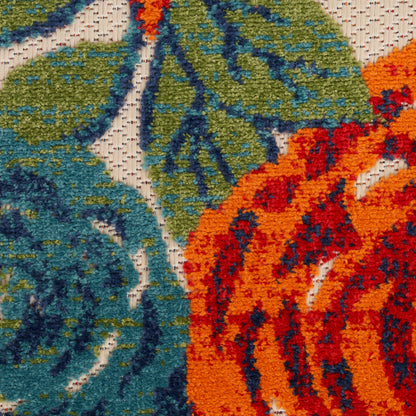 Close-up of a woven outdoor rug runner, 8 ft long, with teal and green leaf motifs on an orange-red background; plush textured pile.